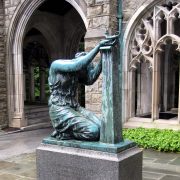 Statue of woman kneeling with head bowed and hands offering something