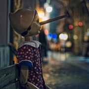 Pinocchio puppet on a rainy cobbled street with coloured lights in the distance
